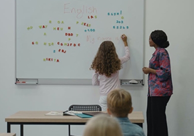 Meisje in klaslokaal voor schoolbord en juf